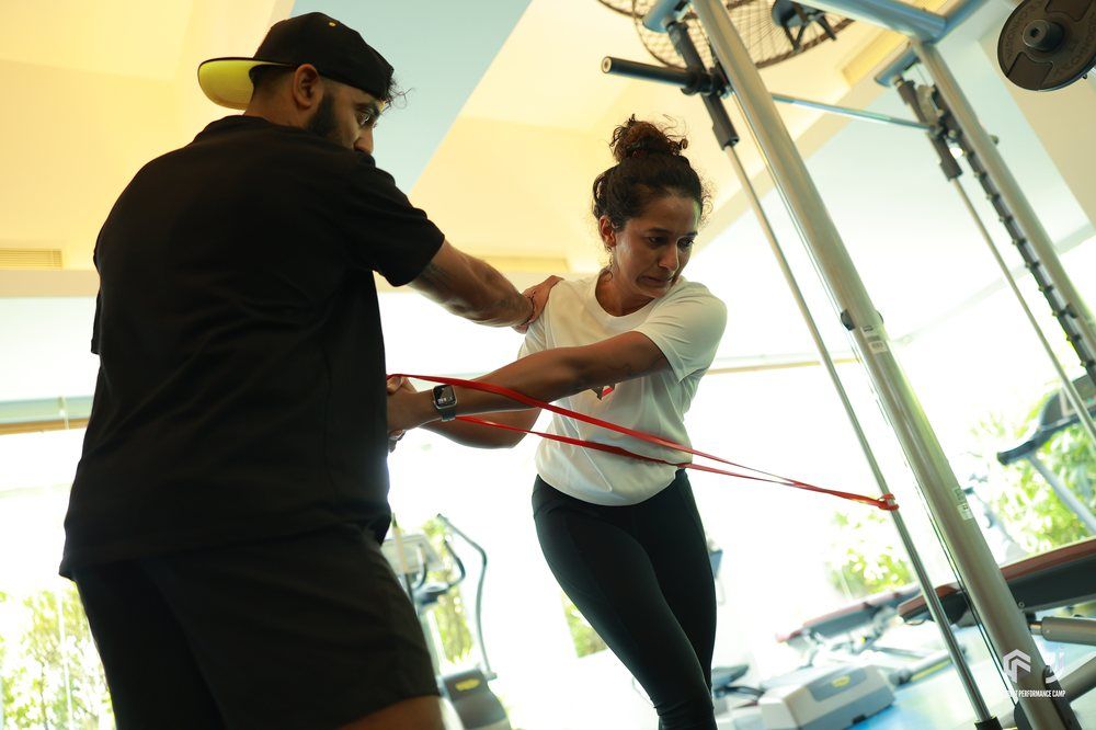 Kiran Mistry coaching a player through resistance-band work